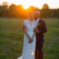 grooms kisses bride on cheek in the sunset