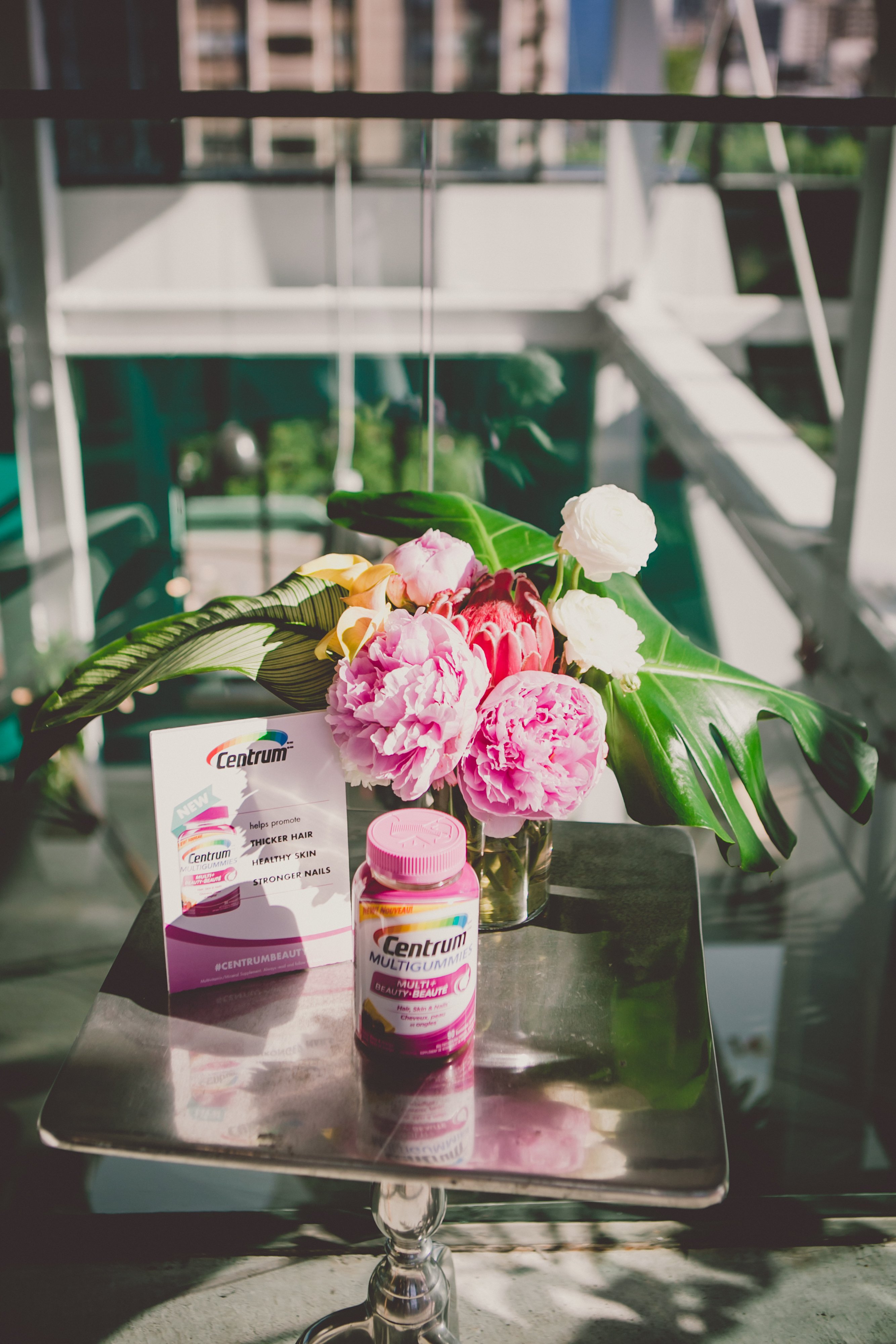 Centrum multivitamins, pink peonies and tropical leaves styling product display. 