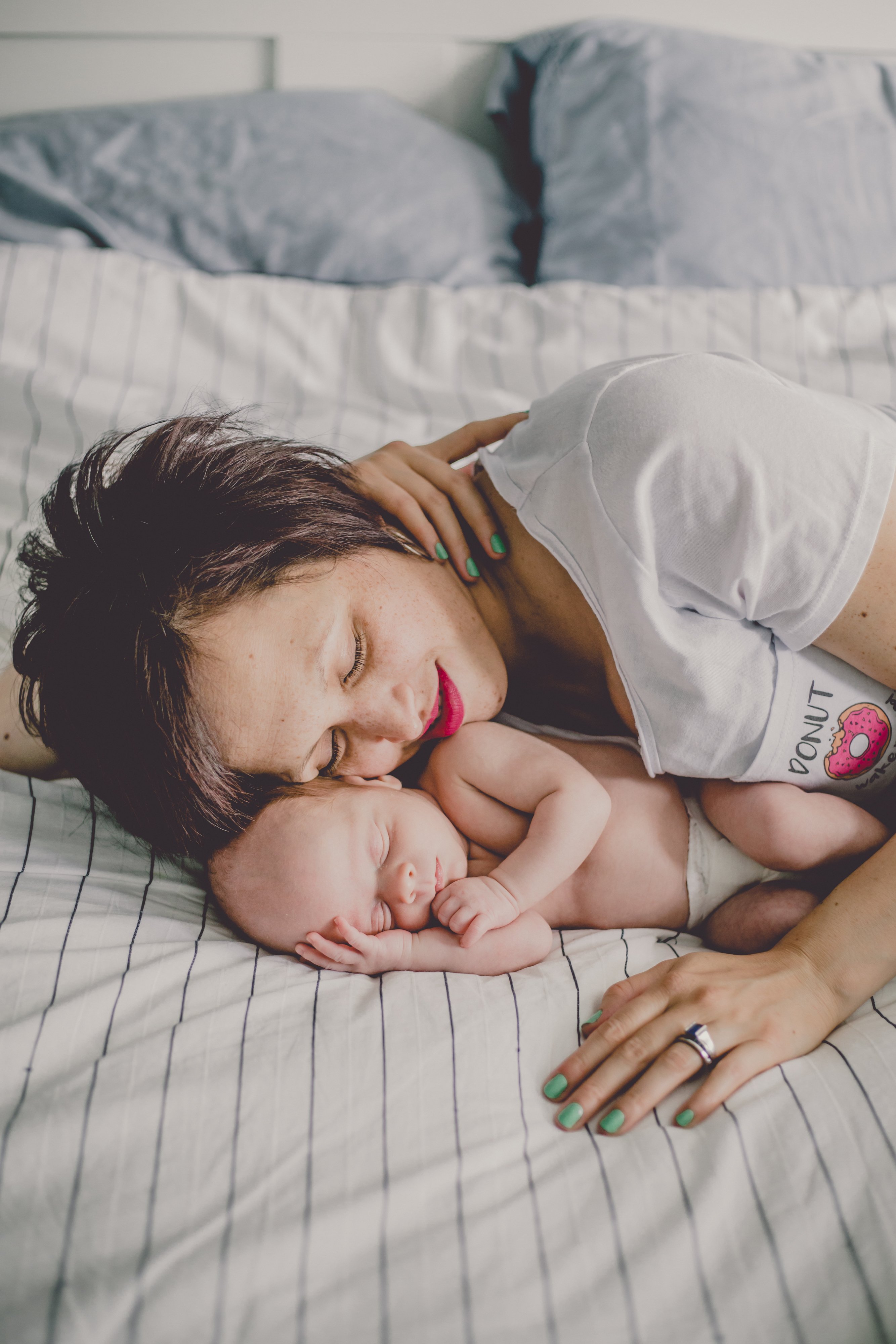 April Maciborka of Olive Studio in Canada photographs new mom Mandy as she snuggles one of her newborn twins. 