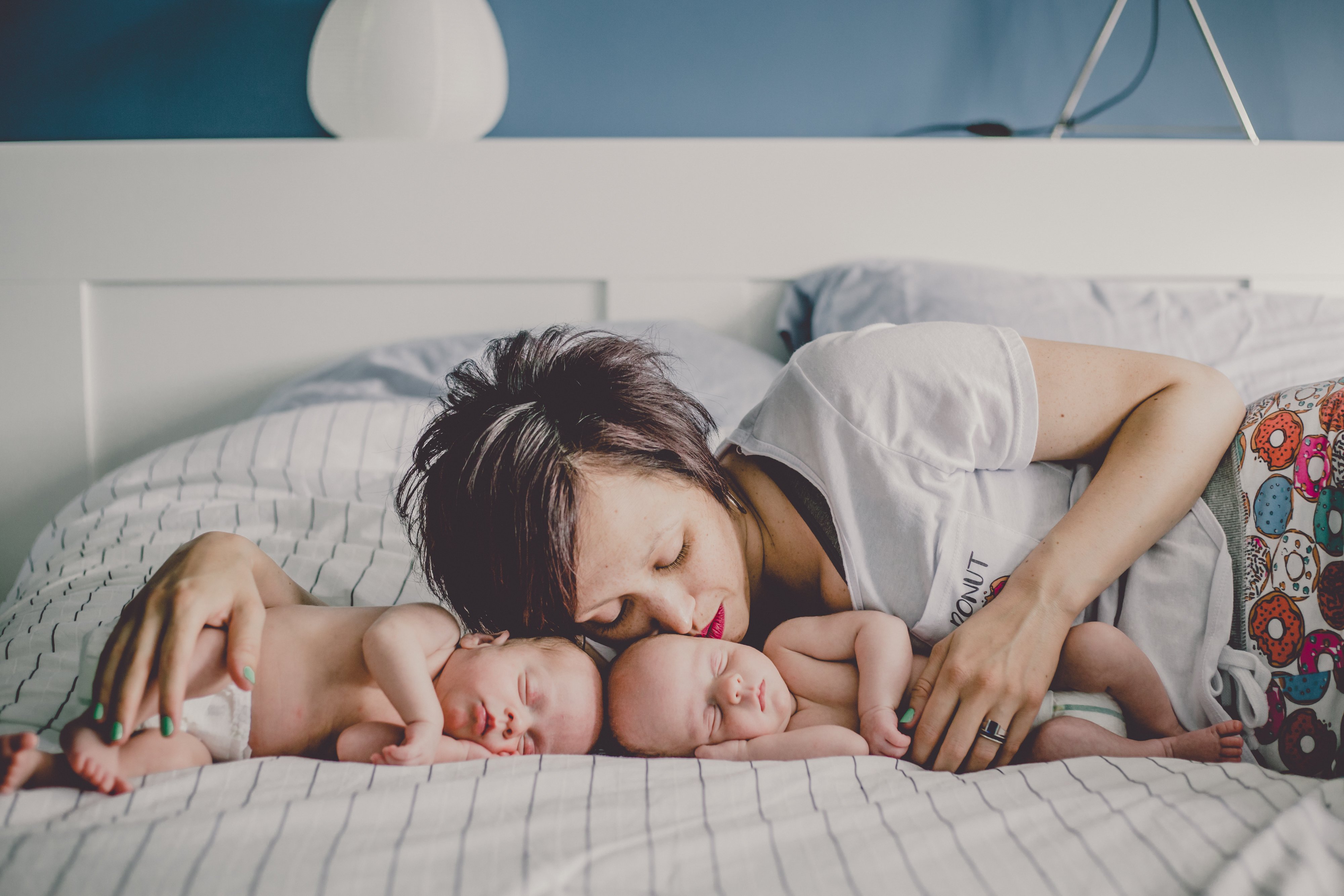 New mom Mandy nestles her sleeping newborn twins Aiden and Nolan while photographed by Olive Studio in Toronto. 