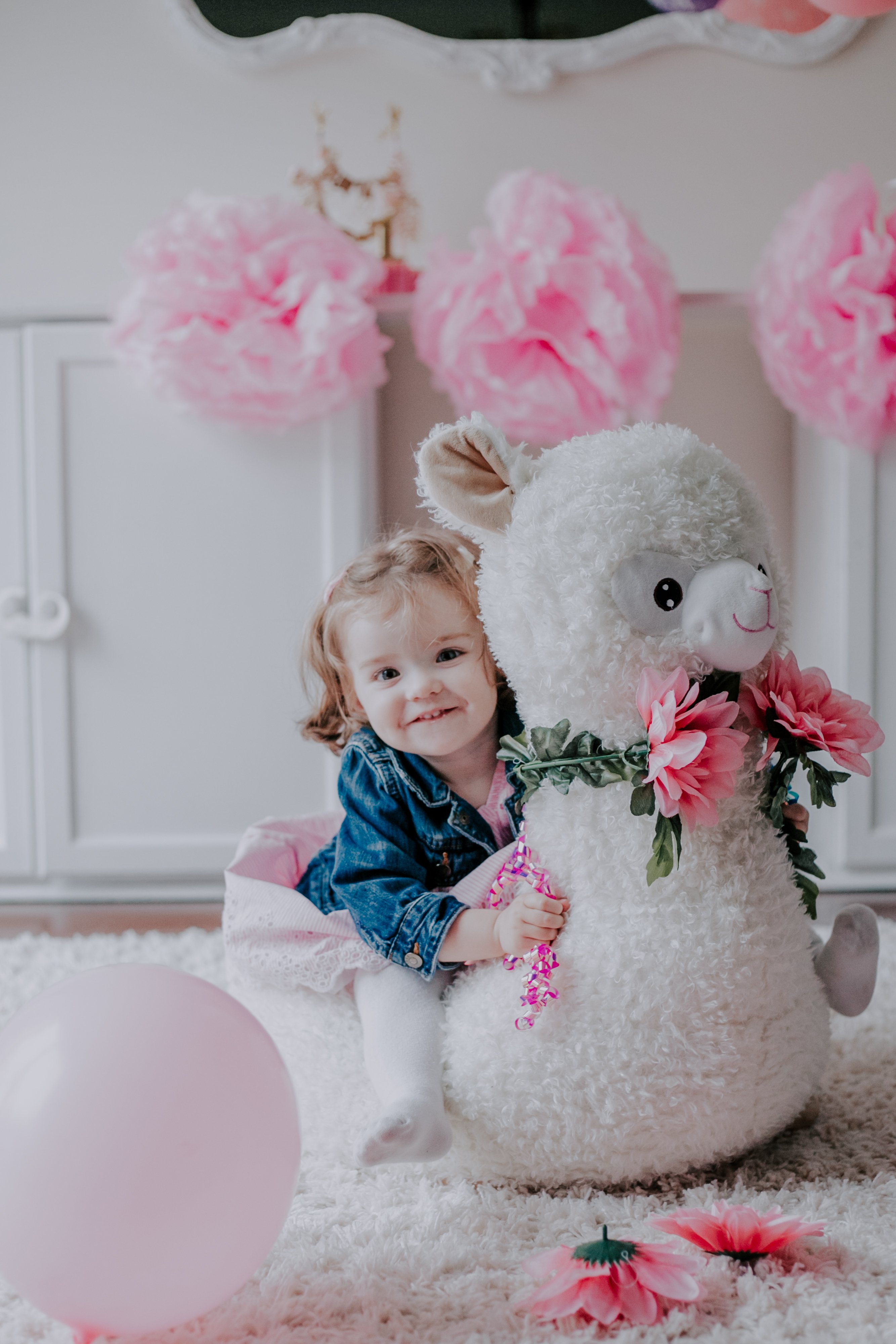 One-year-old Josie sitting on the cutest toy llama at her Cake Smash Session, documented by Olive Studio Photography