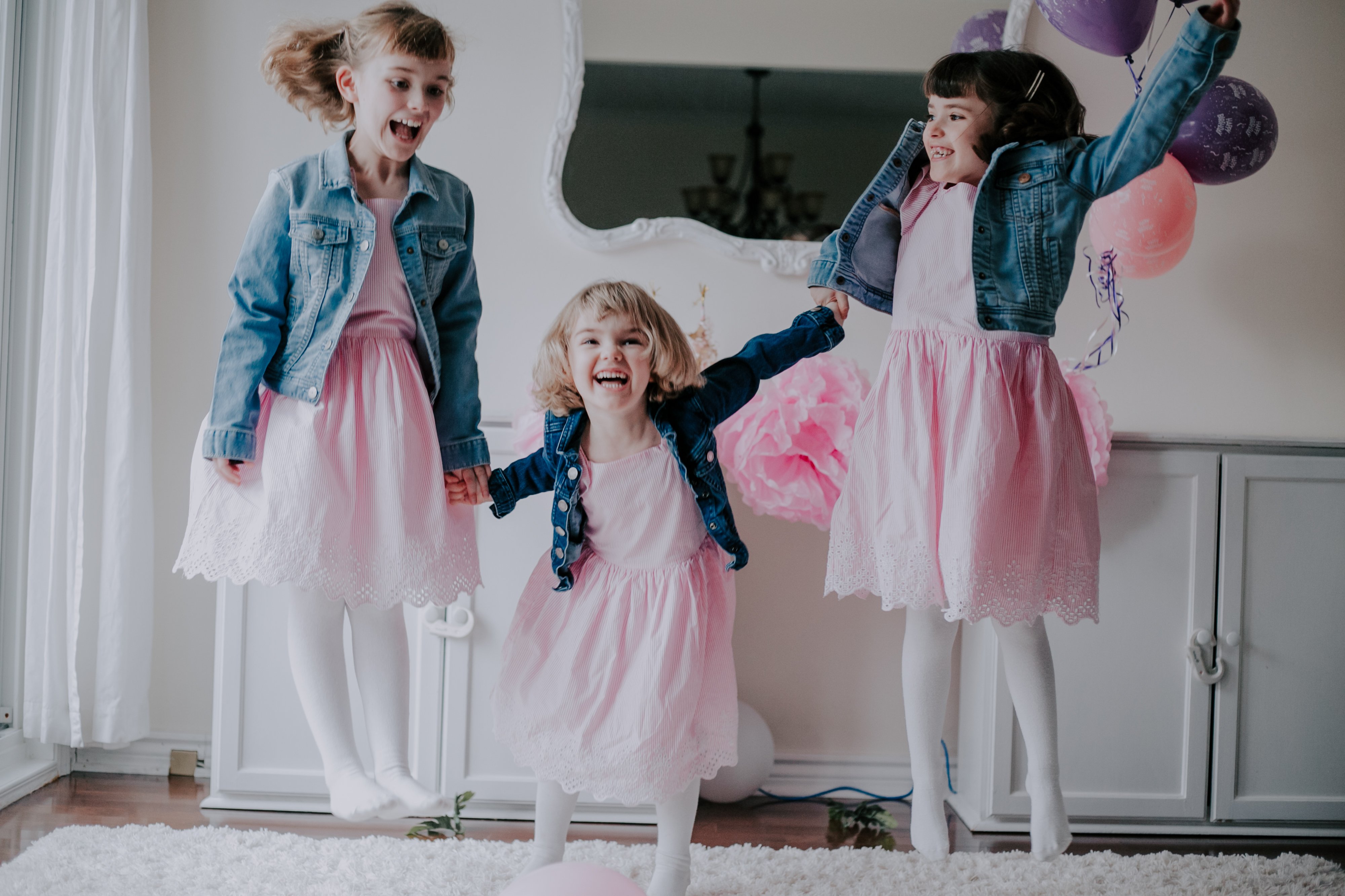 Three sisters jump for joy at their baby sister's Cake Smash Session in Toronto; photographed by Olive Studio Photography 