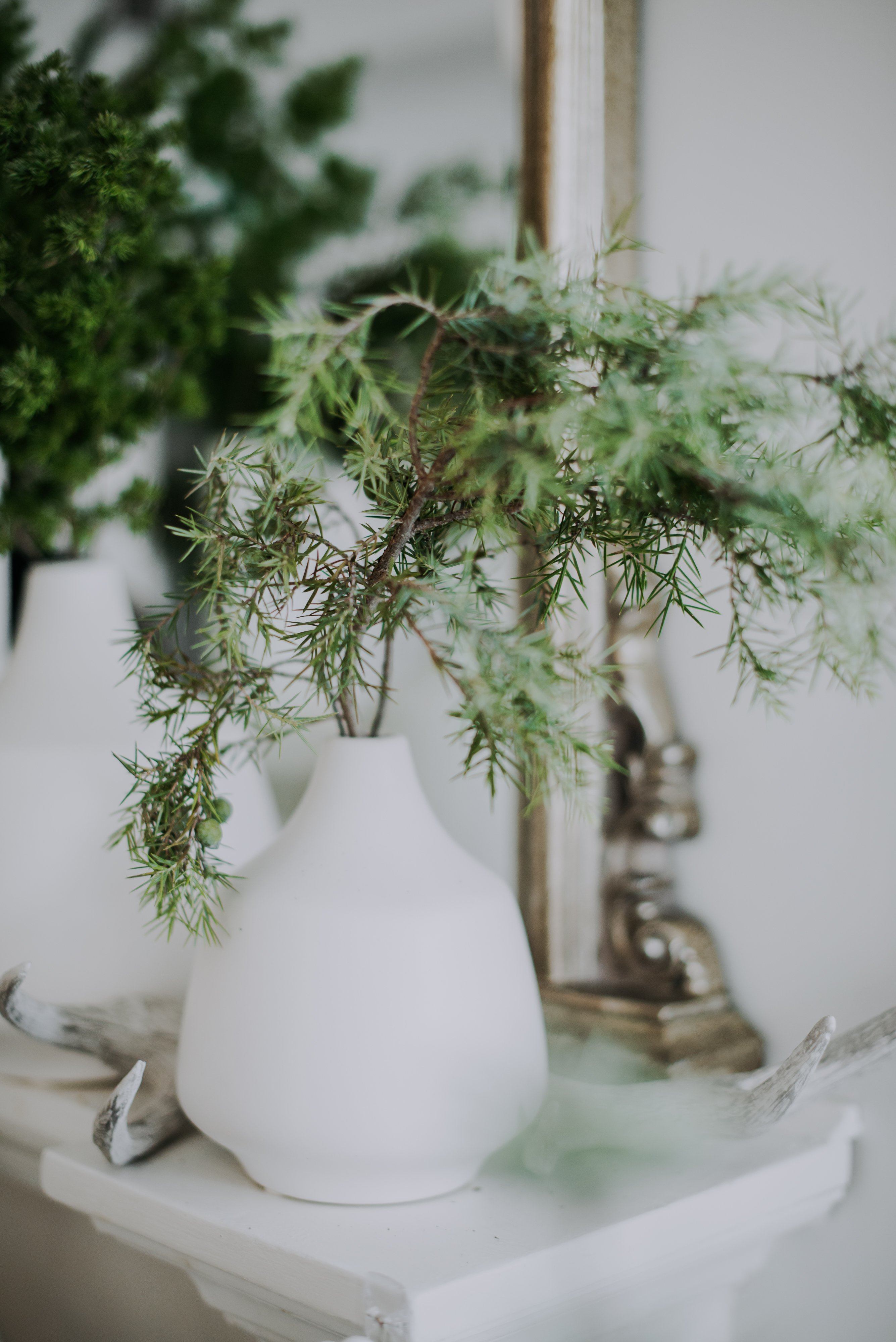 A minimalist ceramic vase with a narrowed top is adorned with two sprigs of pine twigs to accentuate the holiday spirit at Reitmans Holiday Brand Activation Brunch styled by Olive Studio in Toronto. 