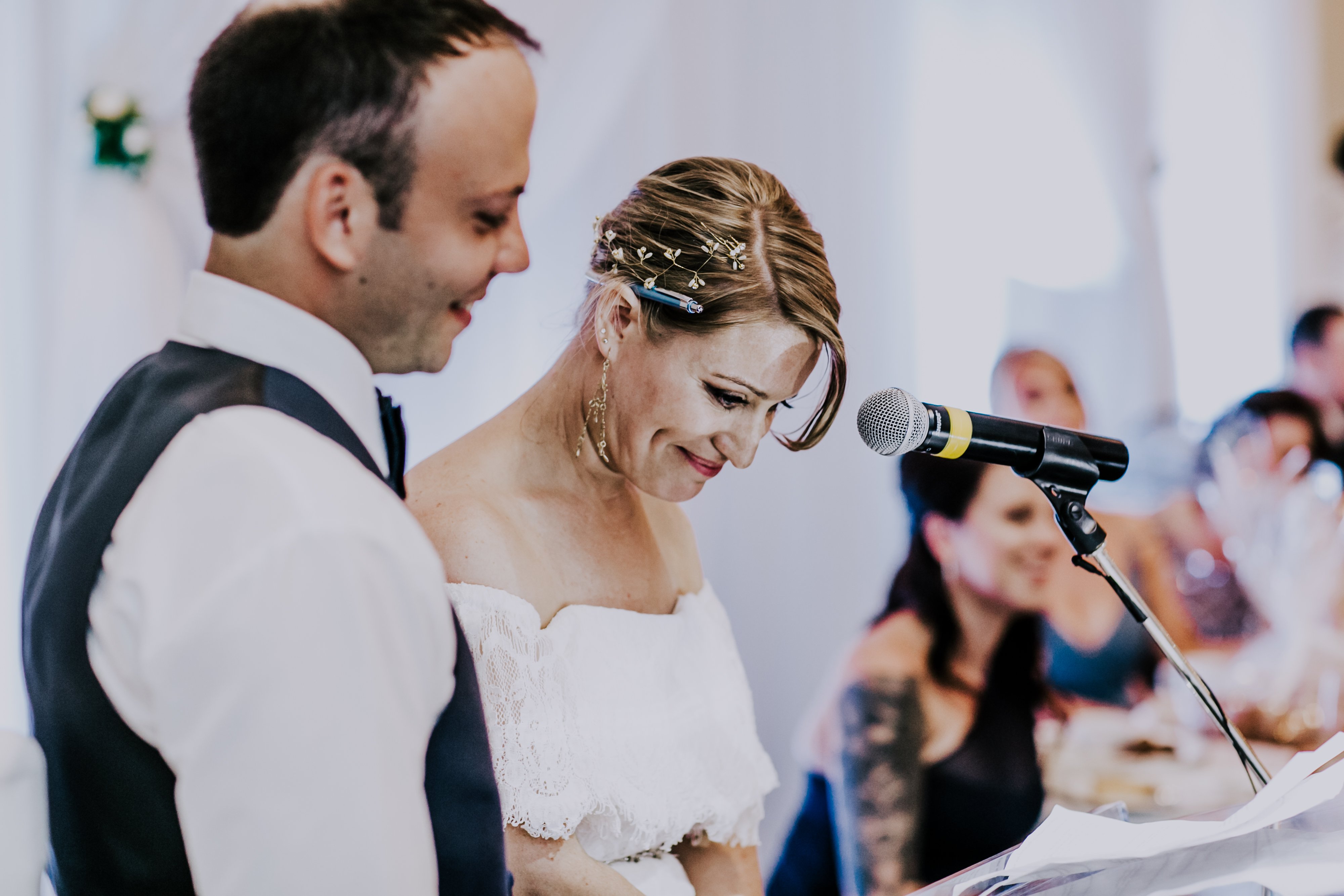 groom stands next to bride while she says speech at their wedding
