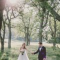 bride and groom walk through long grass