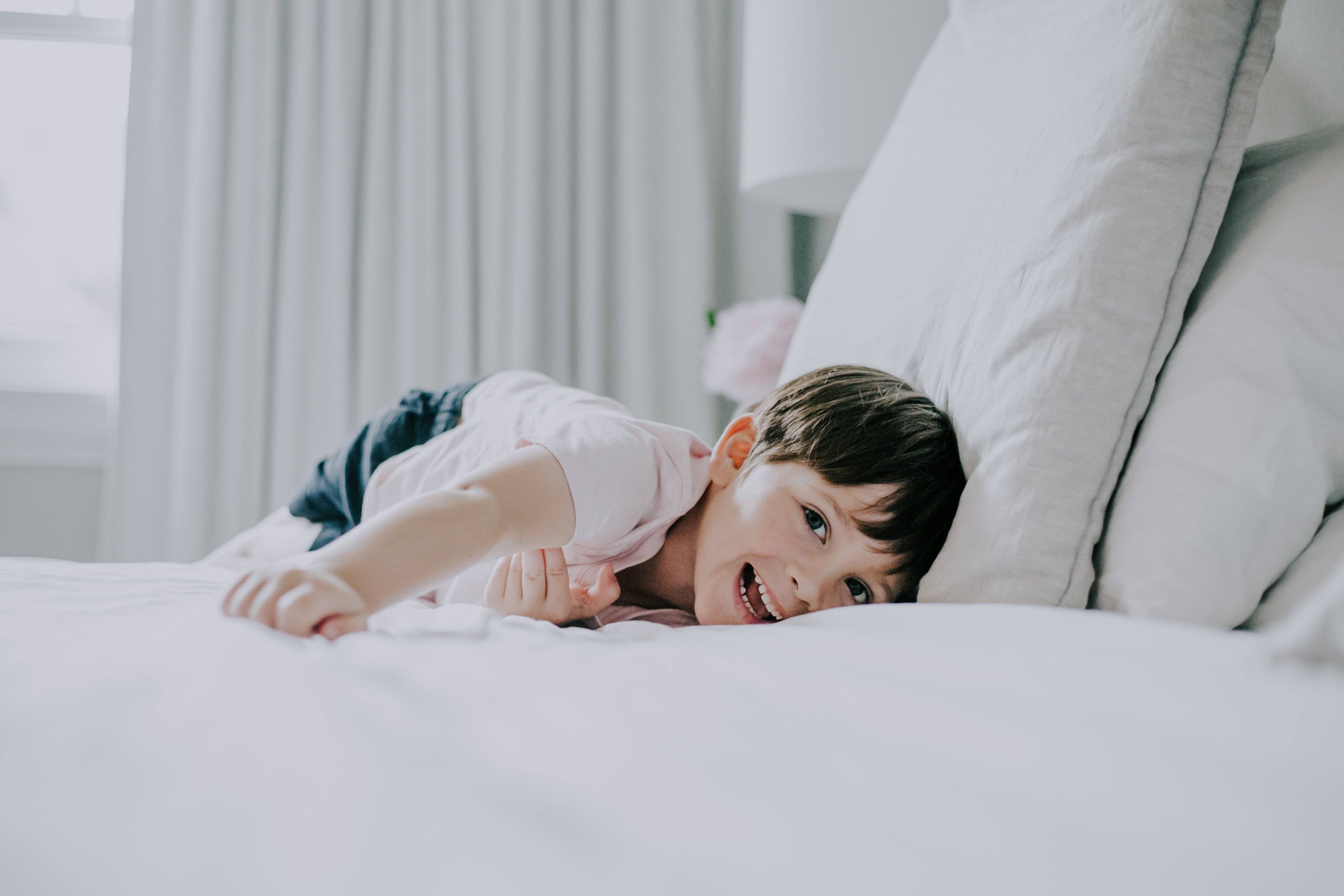 lifestyle family session of boy laughing on a bed