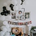 a black and white balloon garland over fireplace mantle with framed photos and presents