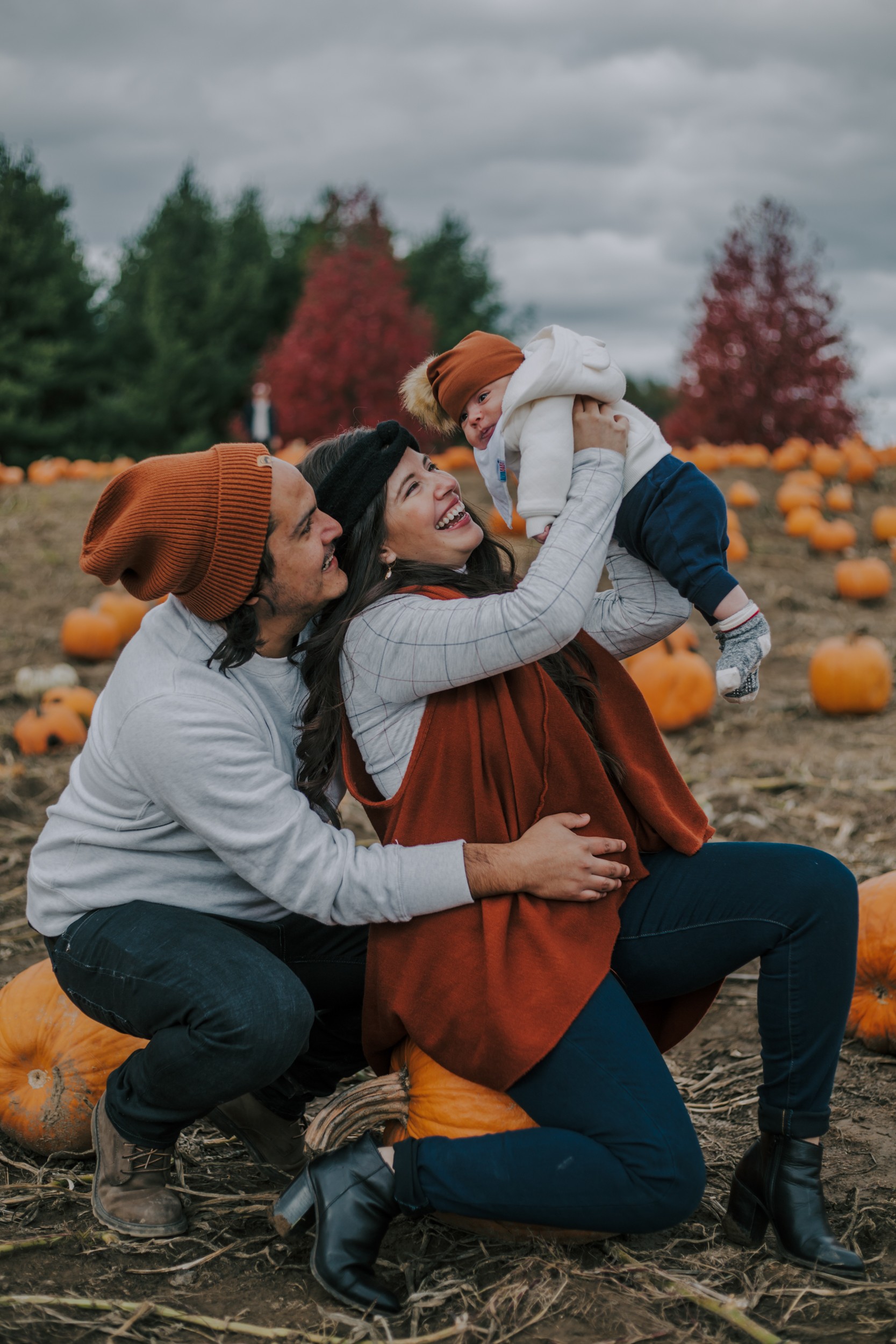 family portrait in a pumpkin patch of small baby with mother and father