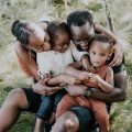 a young black family embraces on the grass