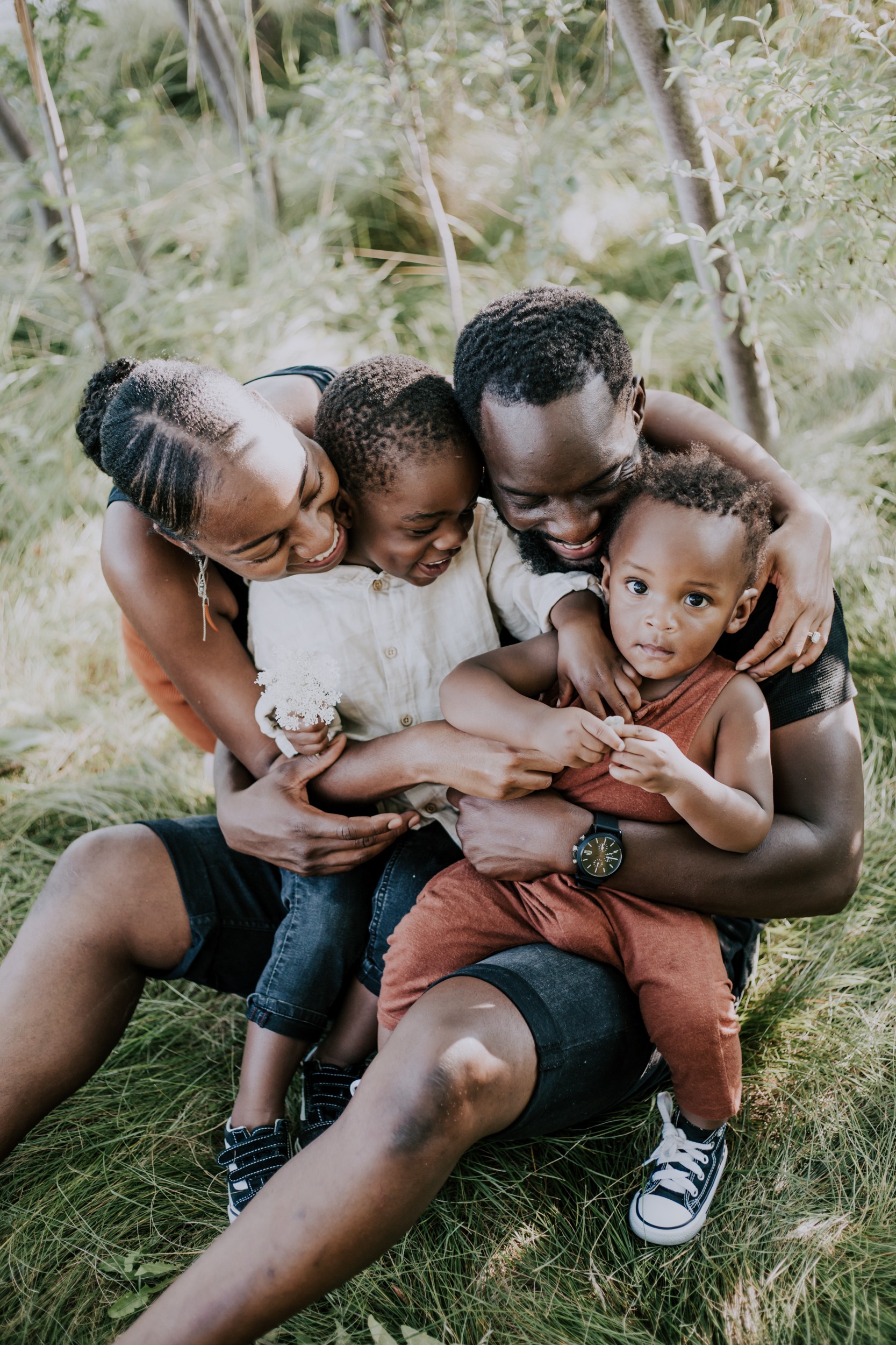a young family hugs one another on the grass