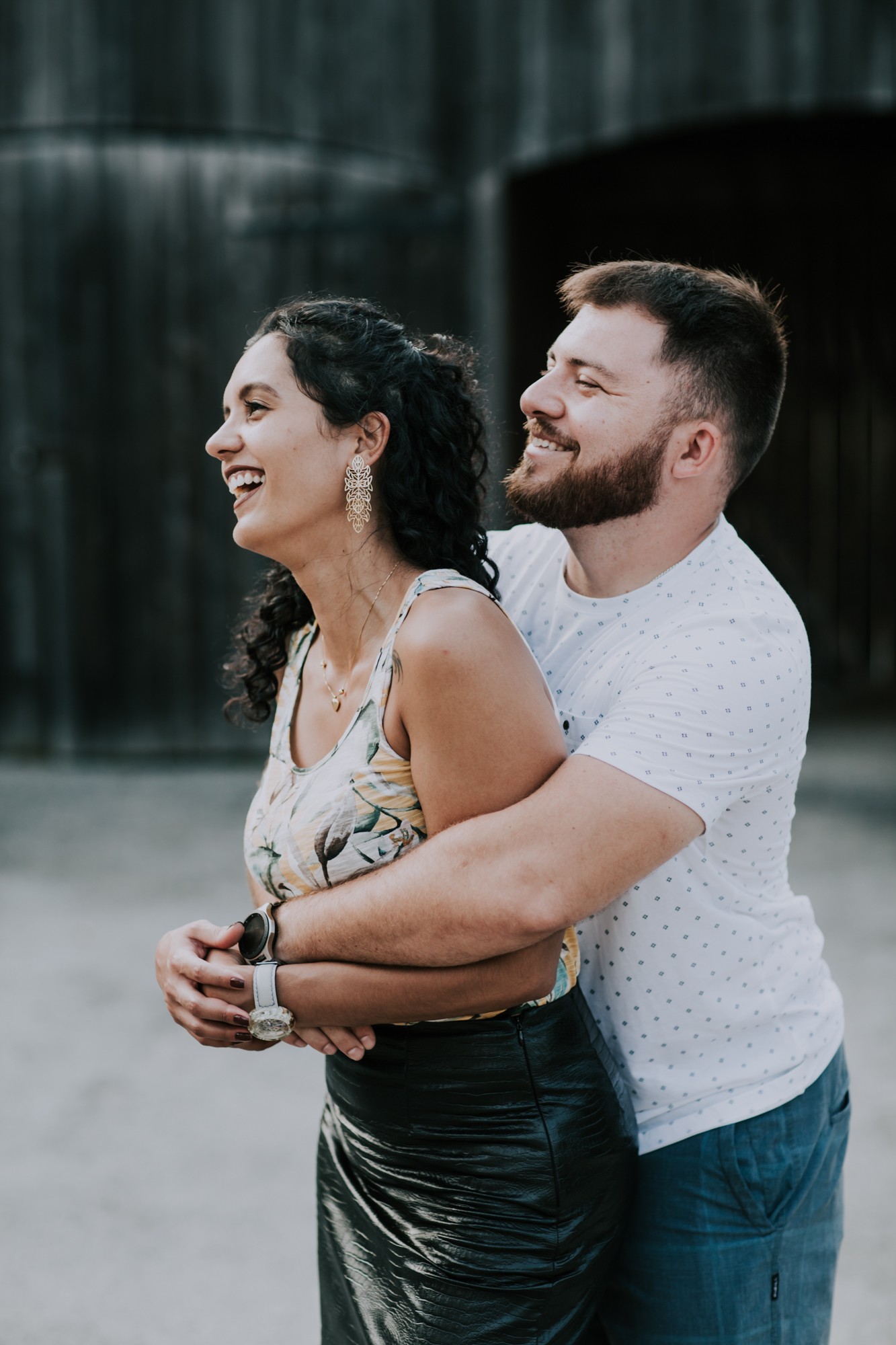 man embraces woman from behind while smiling