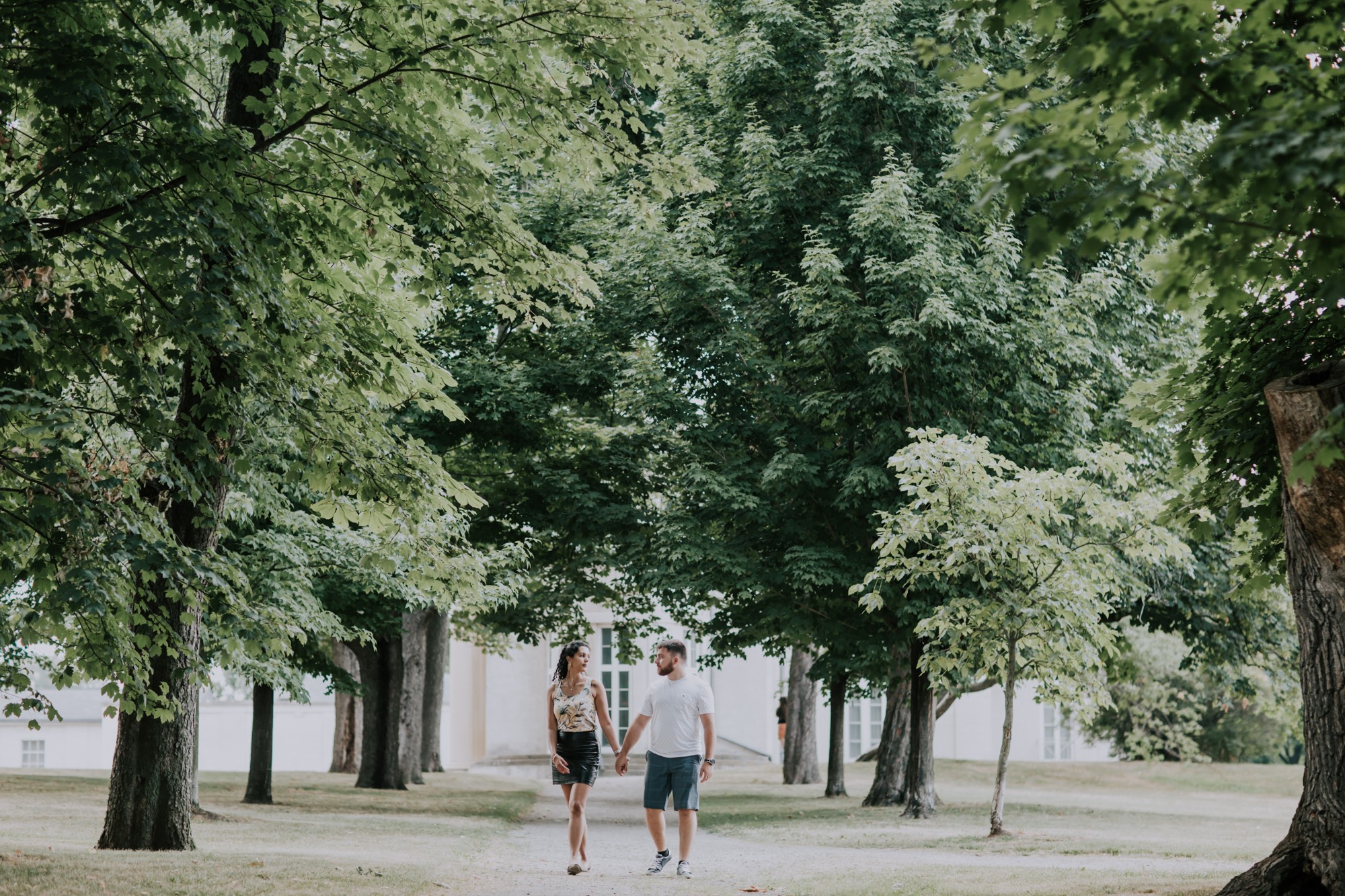 couple walk hand in hand on tree lined road