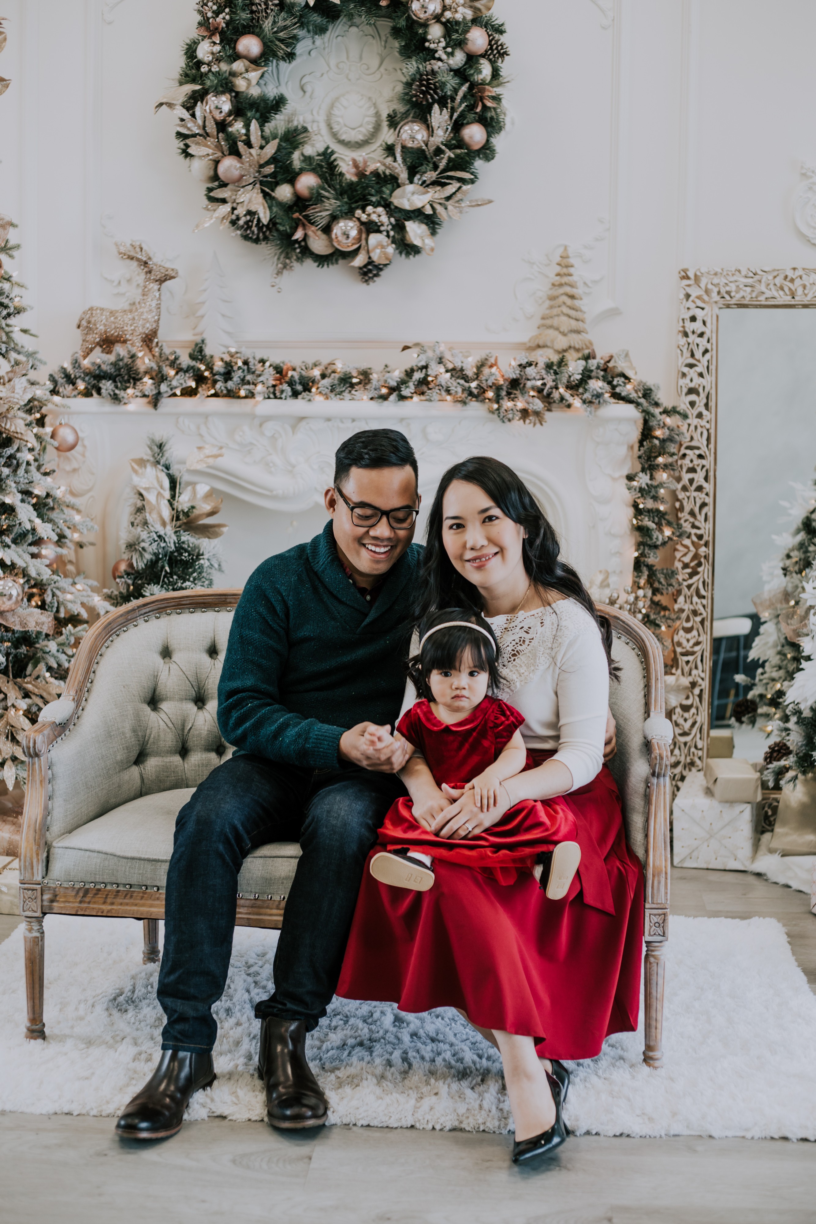 asian couple hold baby daughter in front of xmas tree