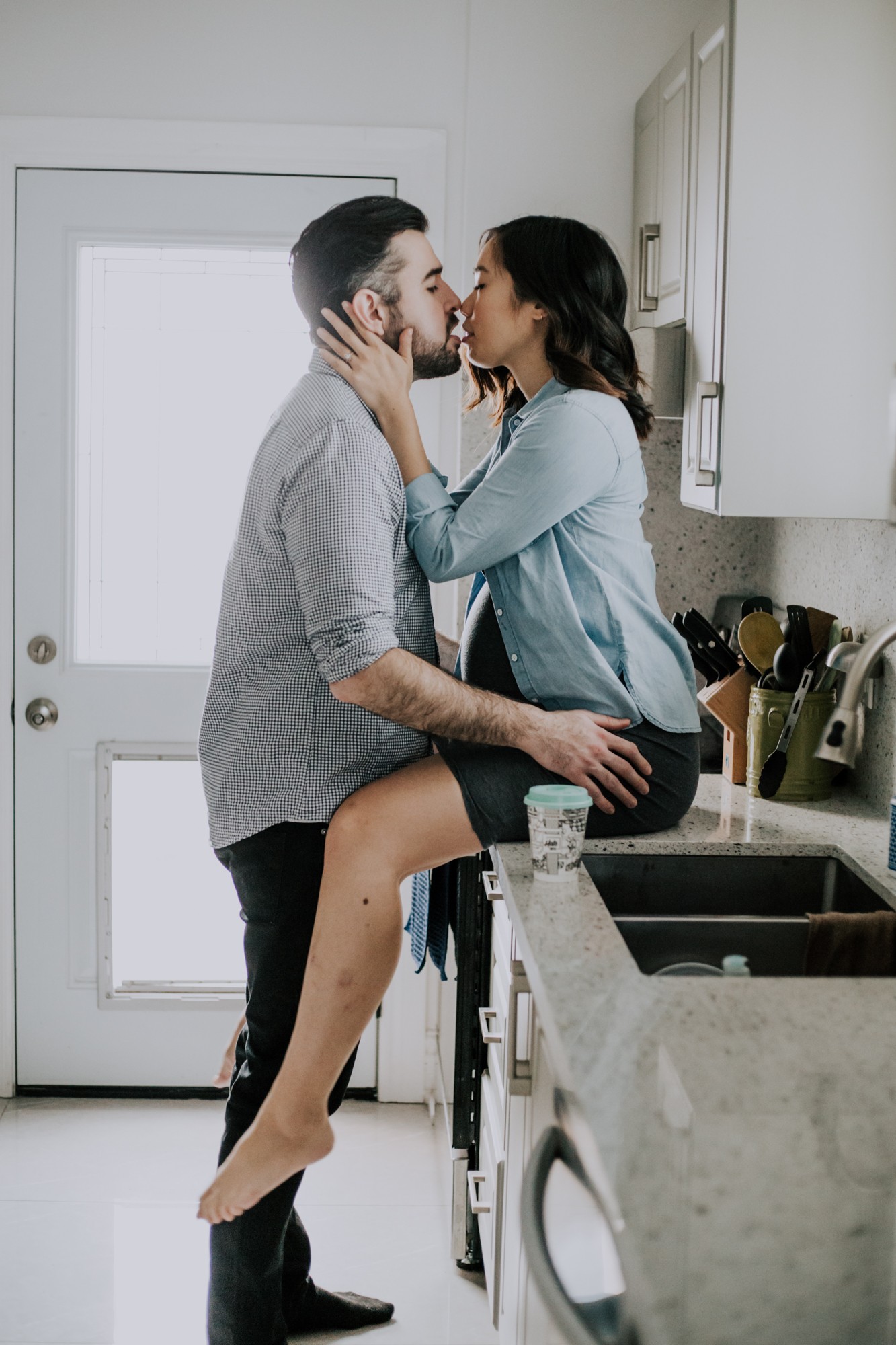 couple kissing in the kitchen for maternity session
