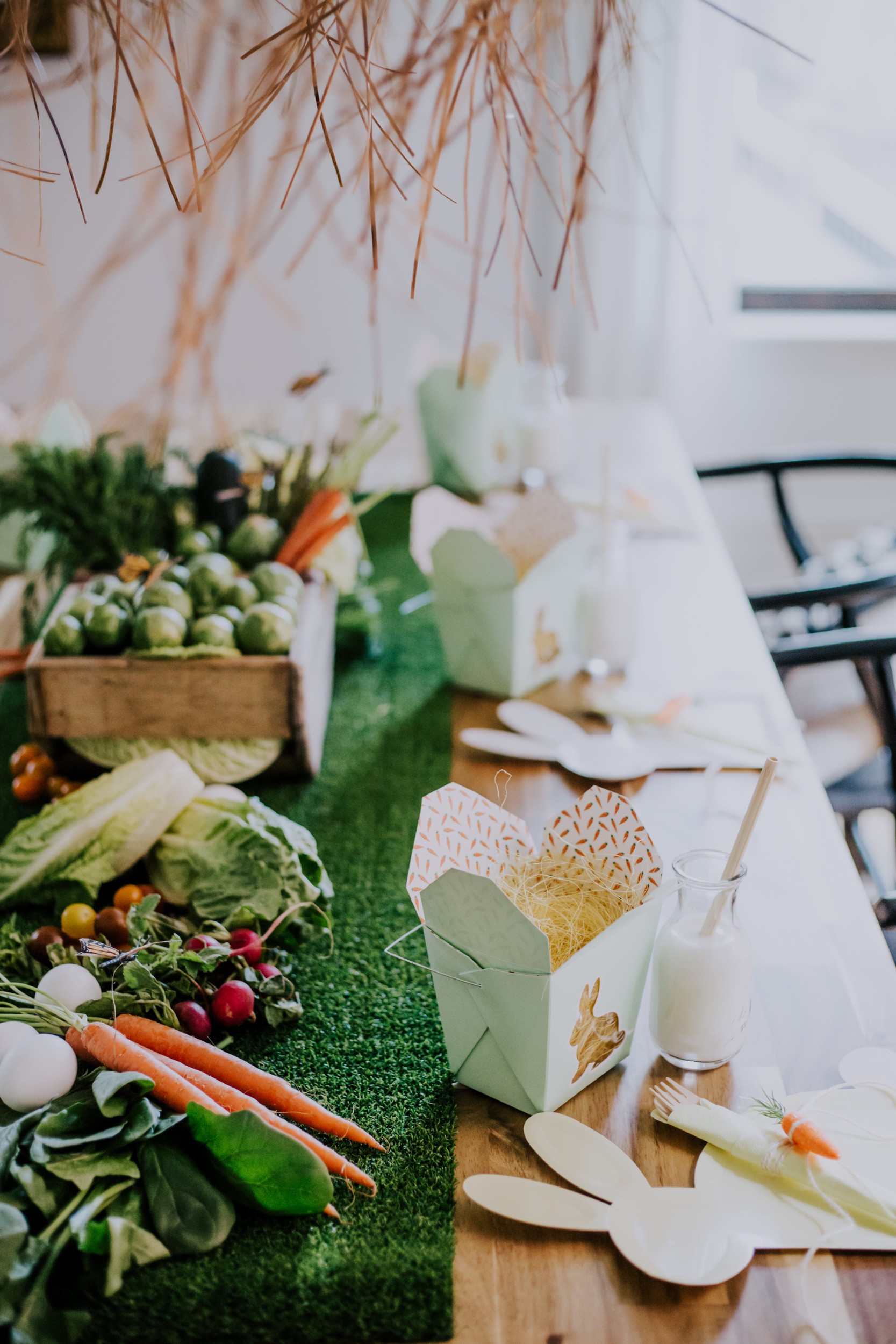 an Easter brunch tablescape hosts a veggie table runner, bunny plates and take-out boxes for an easter egg hunt
