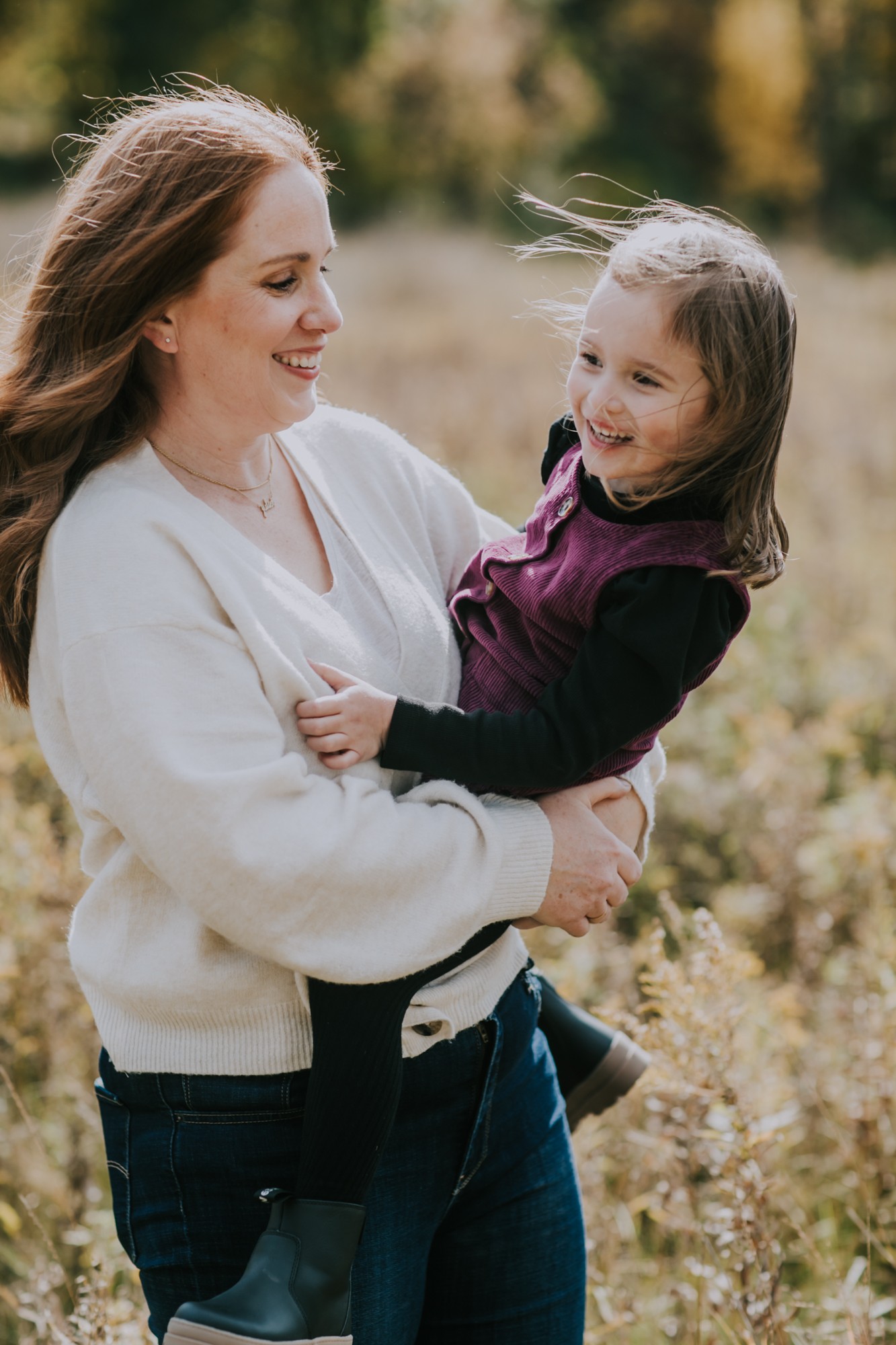 mother and daughter laugh in grassy field