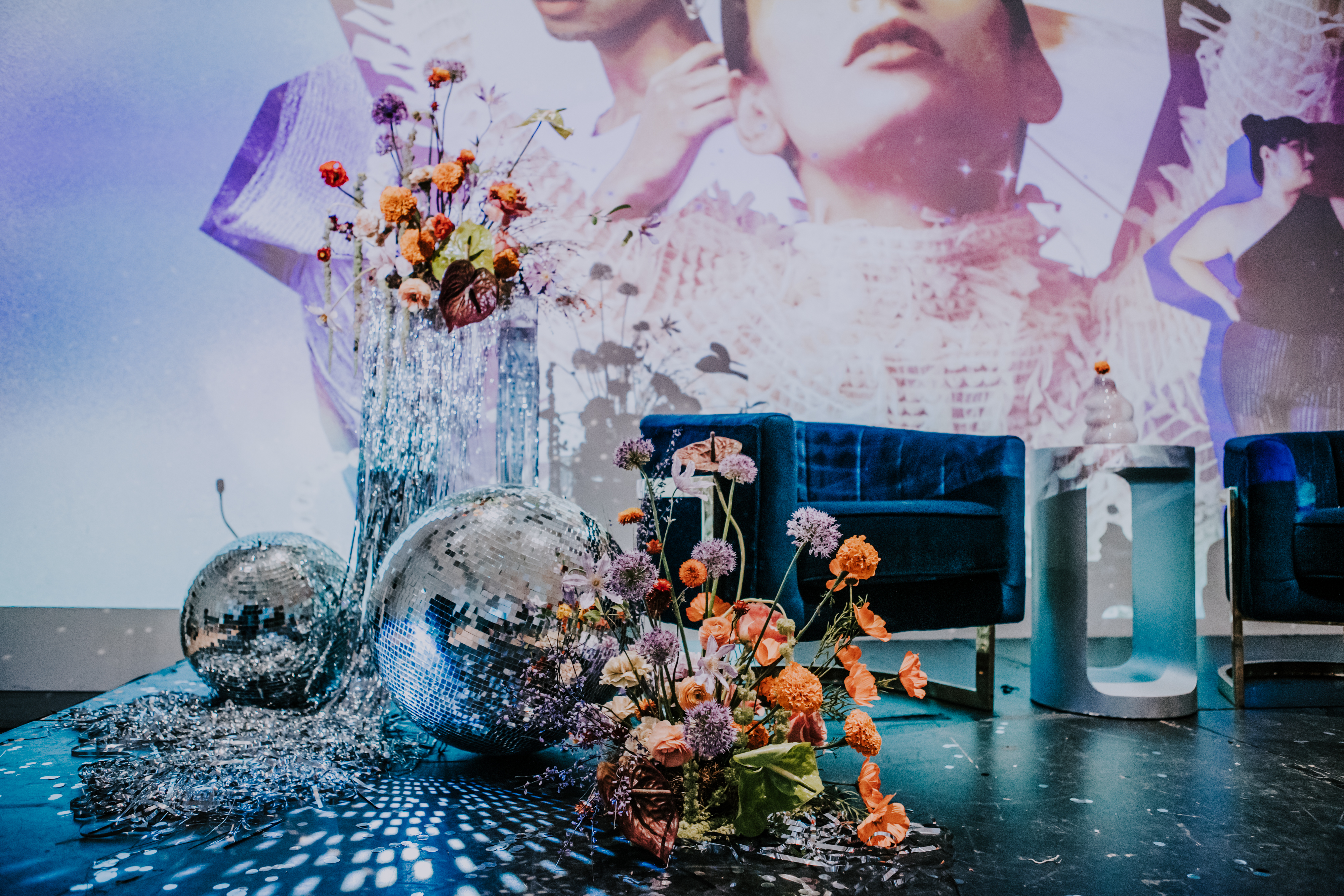 Pinterest Predicts Trends Event 2023 stage design with disco balls, blue velvet chairs and orange and lavender flowers